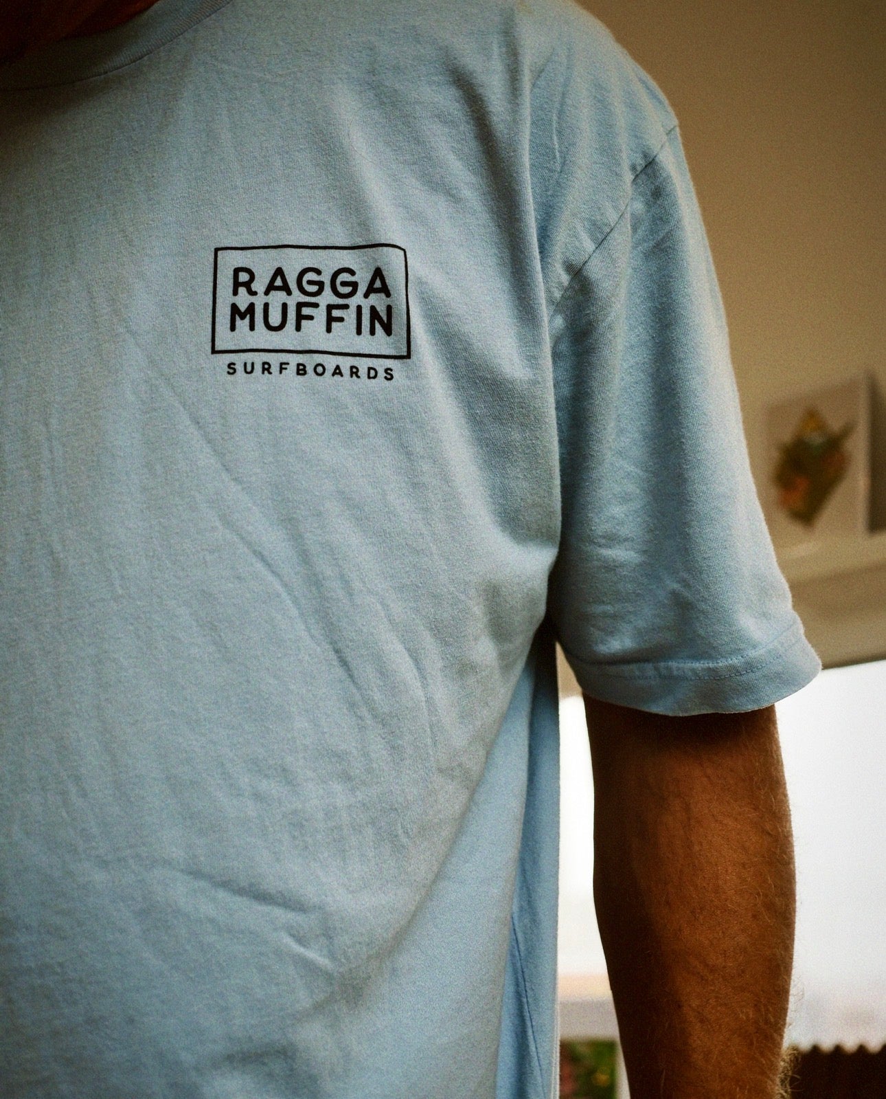 Light blue t-shirt with 'Ragga Muffin Surfboards' logo