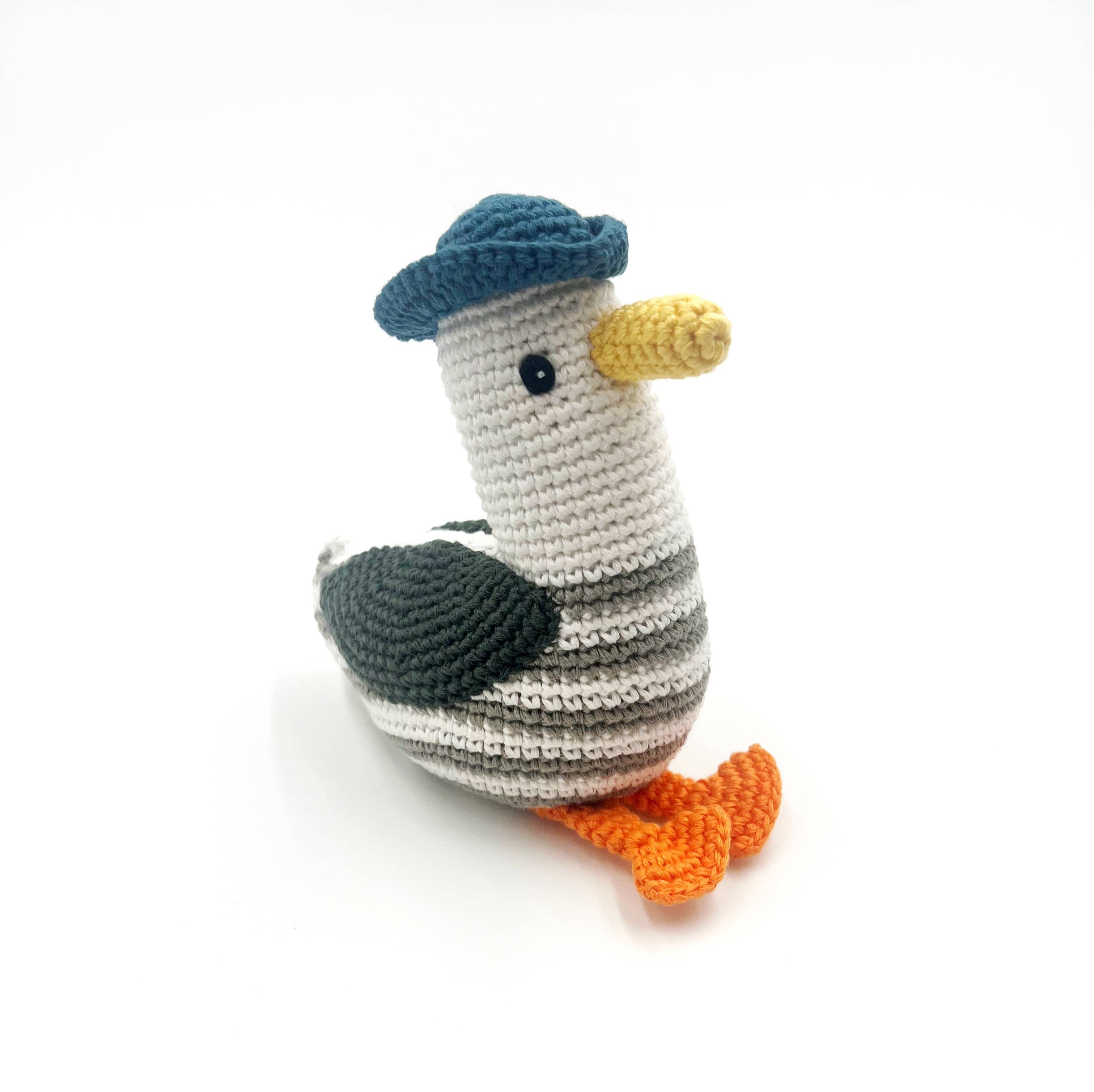 Crocheted bird toy with a blue hat on a white background